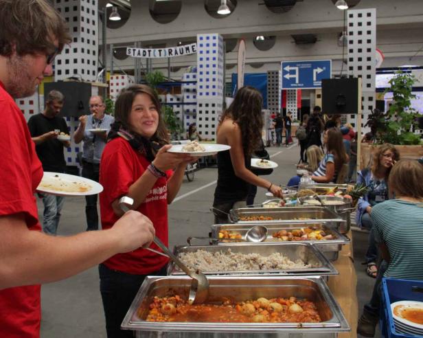 Menschen bedienen sich an einem Buffet mit verschiedenen Speisen.