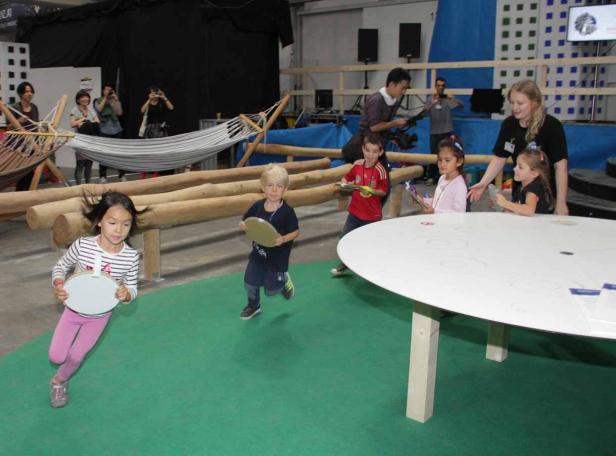 Mehrere Kinder spielen in einem Innenraum mit runden Gegenständen.