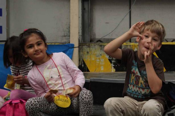 Zwei Kinder sitzen und essen; ein Junge macht Grimassen.