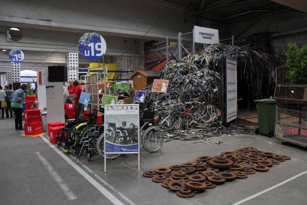 Eine Ausstellung mit Rollstühlen, einem Berg aus Kabeln und rostigen Bremsscheiben.