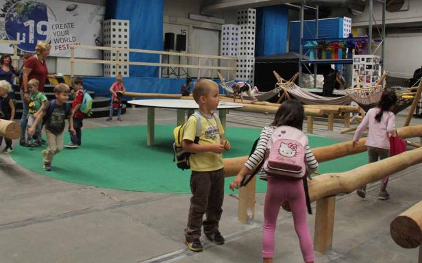 Kinder spielen in einer Indoor-Spielhalle mit Holzbalken und Hängematten.
