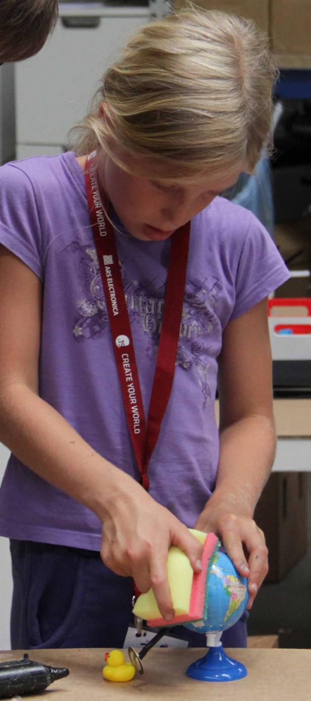 Ein Mädchen putzt einen kleinen Globus mit einem Schwamm.