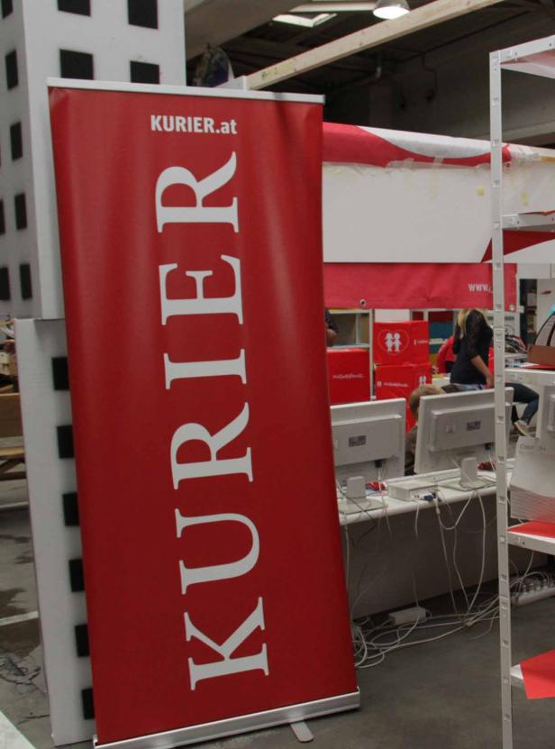 Ein rotes Roll-Up-Banner mit dem Logo von Kurier.at.