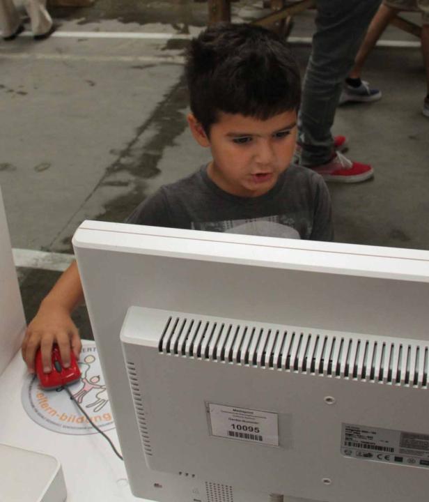 Ein Junge benutzt einen Computer mit einer roten Maus.