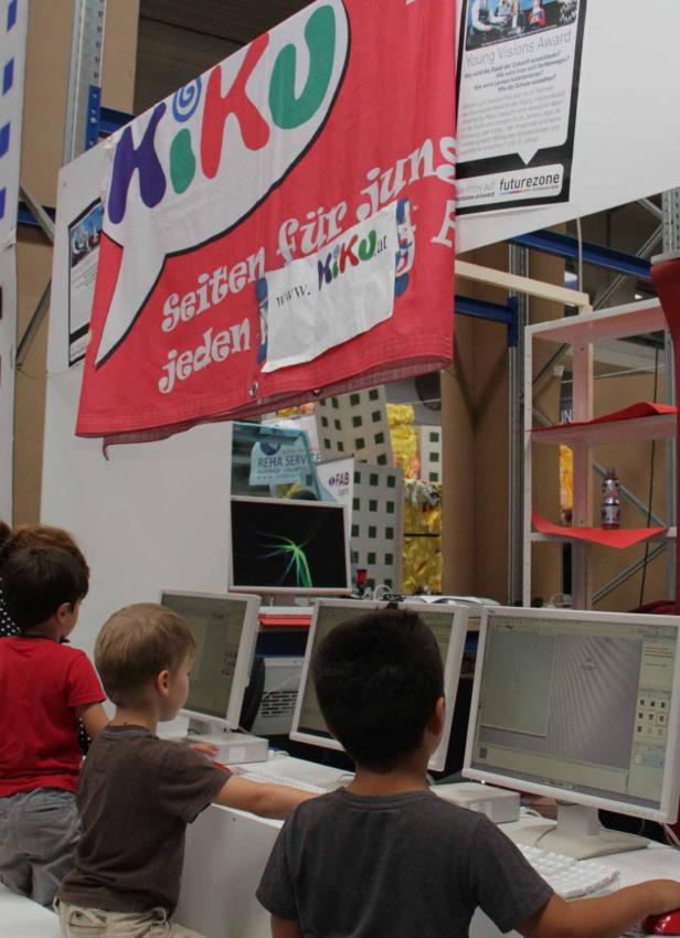 Drei Kinder sitzen vor Computern unter einem Banner von KiKu, einem Jugendportal.