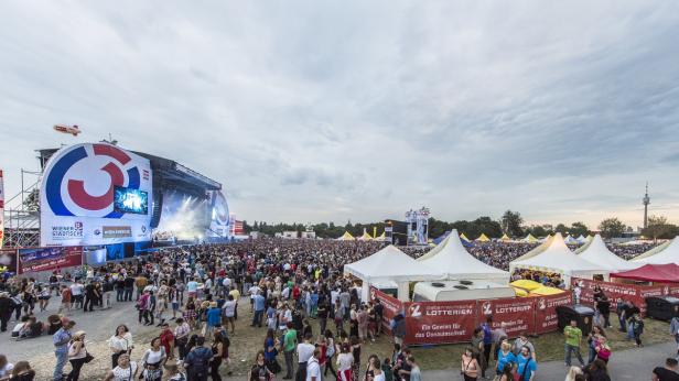 Eine große Menschenmenge beim Donauinselfest vor einer Bühne mit Sponsorenlogos.