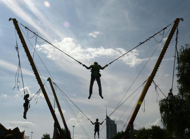 Mehrere Personen nutzen ein Bungee-Trampolin auf einem Jahrmarkt.