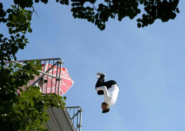 Ein Mann macht einen Rückwärtssalto von einem hohen Sprungturm.