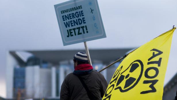 Eine Person demonstriert mit Schildern für „Erneuerbare Energiewende JETZT!“ und gegen Atomkraft.