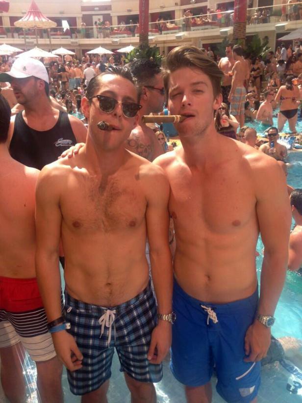 Zwei Männer mit Zigarren posieren in Badehosen in einem Pool.