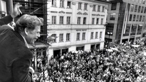 Václav Havel winkt einer Menschenmenge von einem Balkon aus zu.