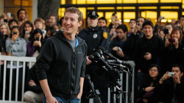 Mark Zuckerberg lächelt vor einer Menschenmenge und Mikrofonen.