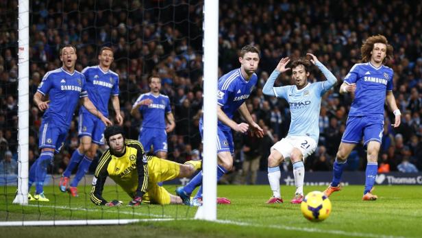 Ein Fußballspieler von Manchester City verpasst das Tor, während Chelsea-Spieler zusehen.