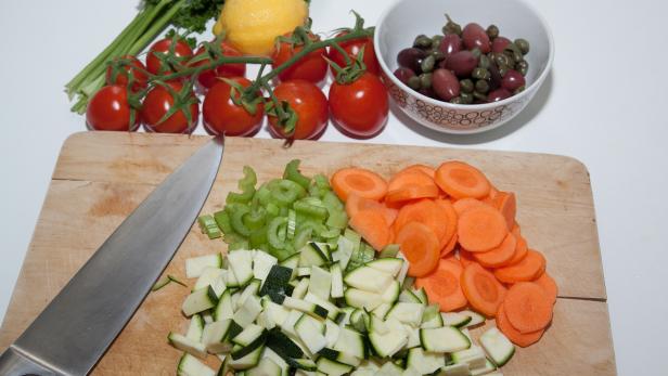 Ein Schneidebrett mit geschnittenem Gemüse, darunter Karotten, Zucchini und Sellerie.