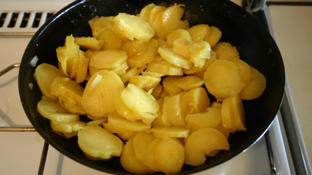 Gebratene Kartoffelscheiben in einer schwarzen Pfanne.