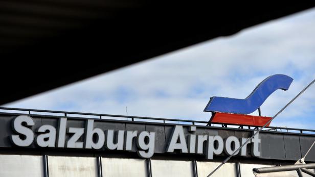 Das Schild „Salzburg Airport“ mit einem blauen und roten Logo auf dem Dach.