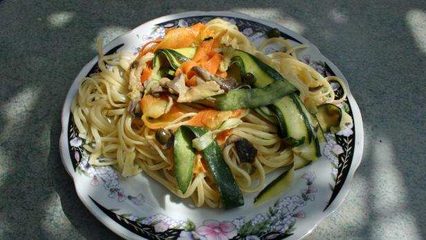 Ein Teller mit Spaghetti, Zucchini, Karotten und Pilzen.