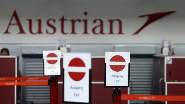 Schilder mit der Aufschrift „Ausgang“ vor einem Austrian Airlines Schalter.