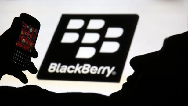 Die Silhouette einer Person mit einem Blackberry-Smartphone vor einem Blackberry-Logo.