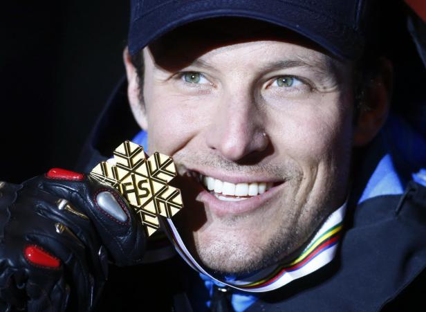Ein lächelnder Skirennläufer mit einer goldenen FIS-Medaille um den Hals.