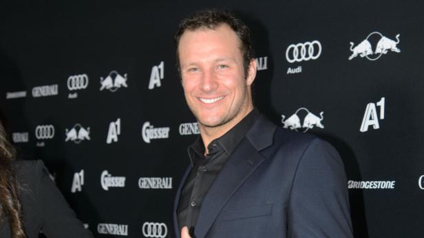 Marcel Hirscher lächelt vor einer Wand mit Sponsorenlogos.