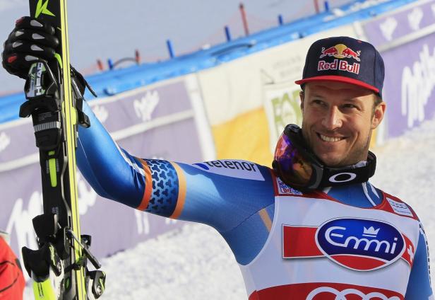 Ein lächelnder Skirennläufer mit Skiern und einer Red Bull-Kappe.