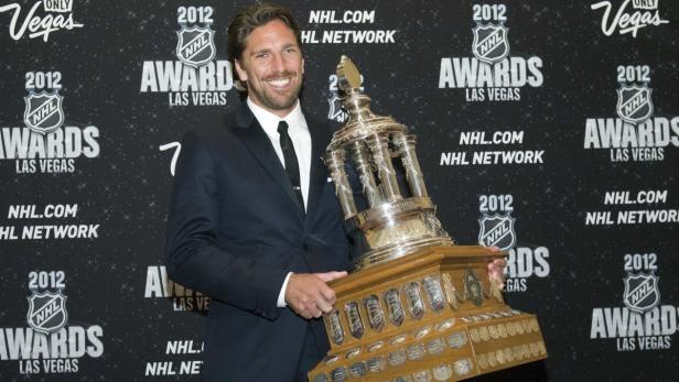 Ein Mann im Anzug hält eine Trophäe vor einem Hintergrund der „NHL Awards Las Vegas 2012“.
