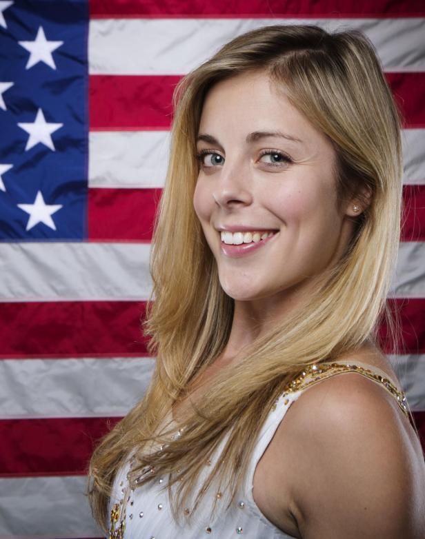 Eine lächelnde Frau posiert vor der US-amerikanischen Flagge.