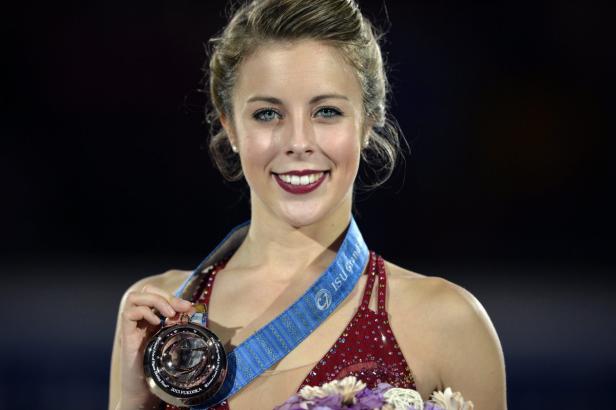 Eine junge Frau mit einer Bronzemedaille um den Hals lächelt.