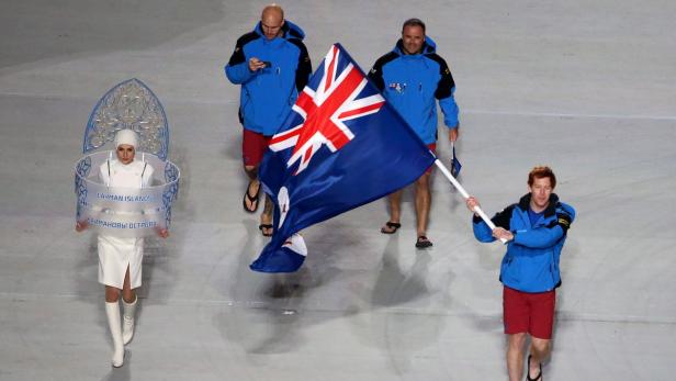 Die Mannschaft der Kaimaninseln bei einer Eröffnungszeremonie mit Flagge und Schild.