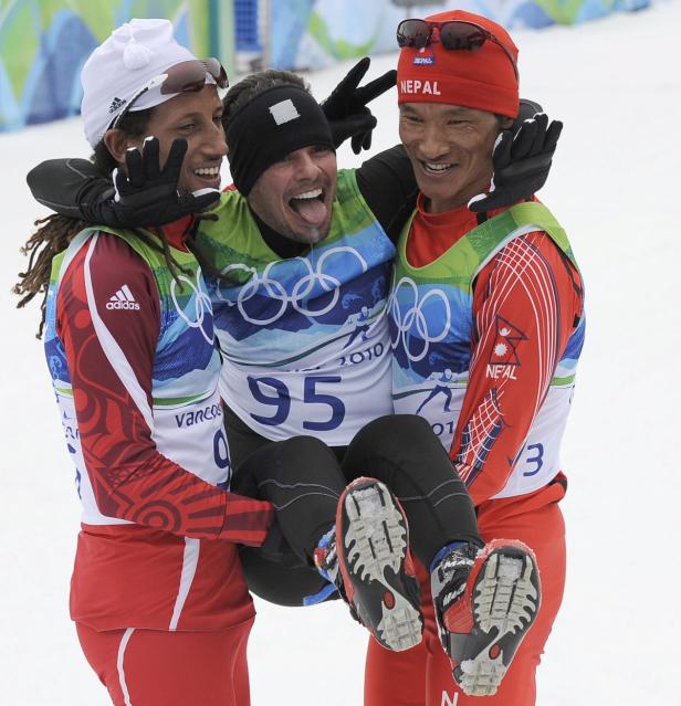 Drei Skilangläufer feiern gemeinsam, einer wird von den anderen beiden getragen.