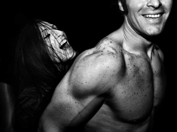 Eine lachende Frau lehnt an der Schulter eines Mannes.