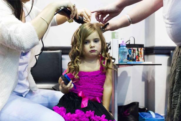 Ein kleines Mädchen bekommt im Friseursalon Locken gemacht.