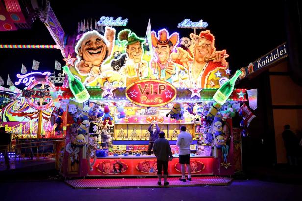 Ein Schießstand auf einem Jahrmarkt mit Karikaturen und dem Schriftzug „V.I.P. Party“.