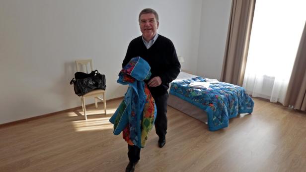 Ein Mann steht in einem Hotelzimmer und hält eine bunte Jacke in der Hand.