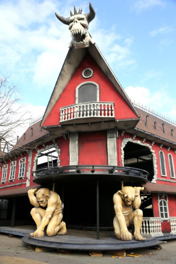 Ein rotes Gebäude mit einem großen Totenkopf mit Hörnern auf dem Dach und zwei Monsterstatuen davor.
