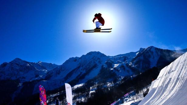 Ein Skifahrer springt vor einer Bergkulisse in der Luft.