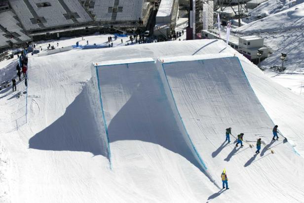 Arbeiter präparieren eine Halfpipe aus Schnee für ein Sportevent.