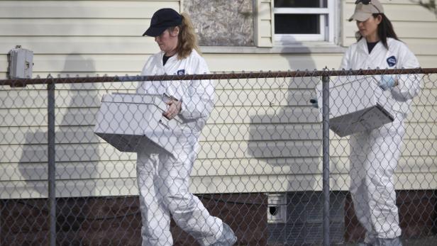 Spurensicherung in Cleveland Zwei Personen in Schutzanzügen tragen Kisten vor einem Haus entlang.