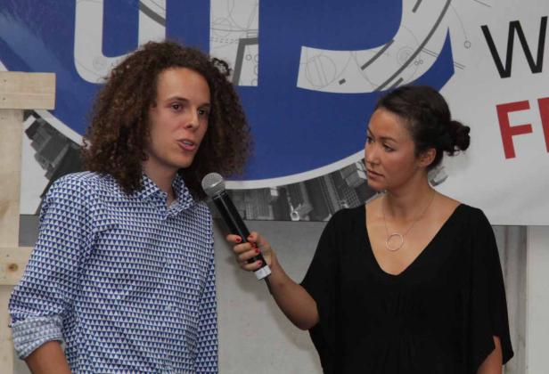 Ein Mann mit lockigem Haar wird von einer Frau interviewt.