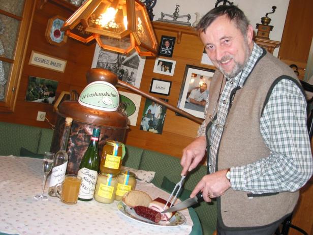 Ein Mann schneidet Wurst und Speck in einer traditionellen Gaststube.