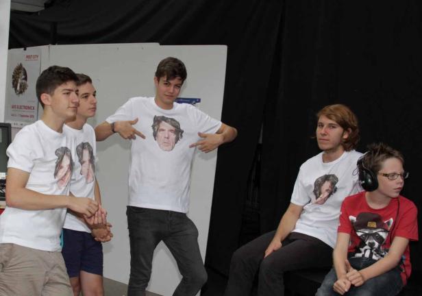 Eine Gruppe Jugendlicher trägt T-Shirts mit aufgedruckten Gesichtern.