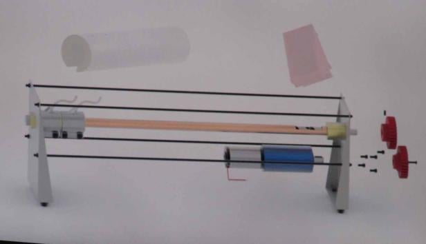 Eine schematische Darstellung einer Maschine mit Zahnrädern, einer Walze und Papier.