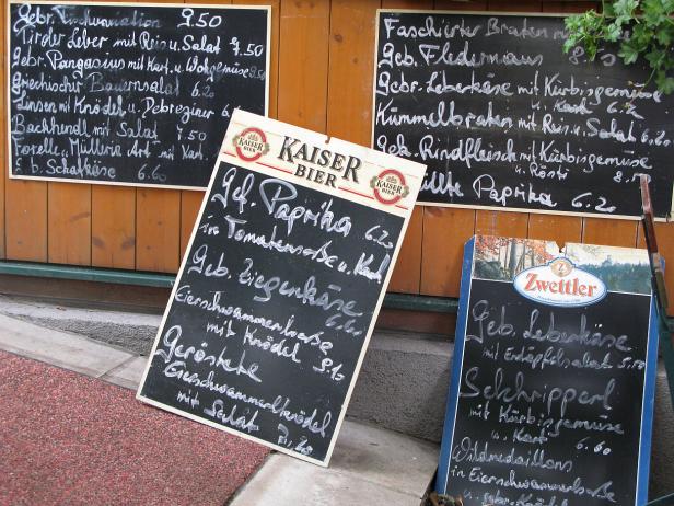 Mehrere Speisekarten mit handgeschriebenen Menüs vor einem Restaurant.