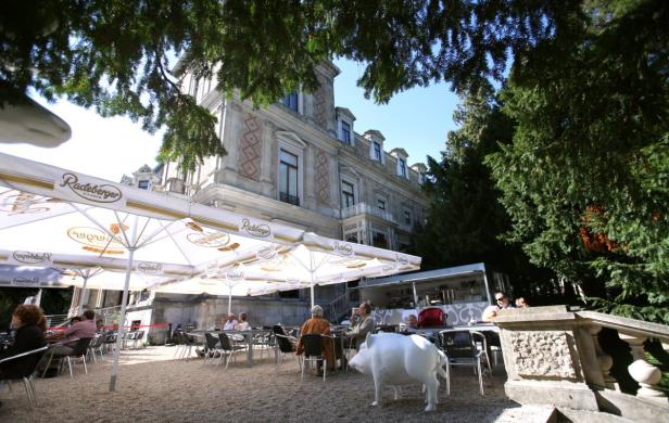 Ein Biergarten mit Radeberger-Sonnenschirmen vor einem historischen Gebäude.
