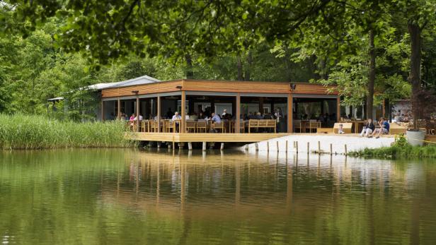 Ein Restaurant am See mit Gästen auf der Terrasse.