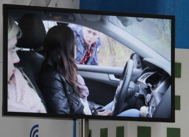 Eine Frau sitzt in einem Auto, während ein Mann sich zum Fenster beugt.