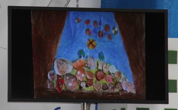 Ein Kinderbild mit vielen Gesichtern und bunten Kreisen vor blauem Hintergrund.