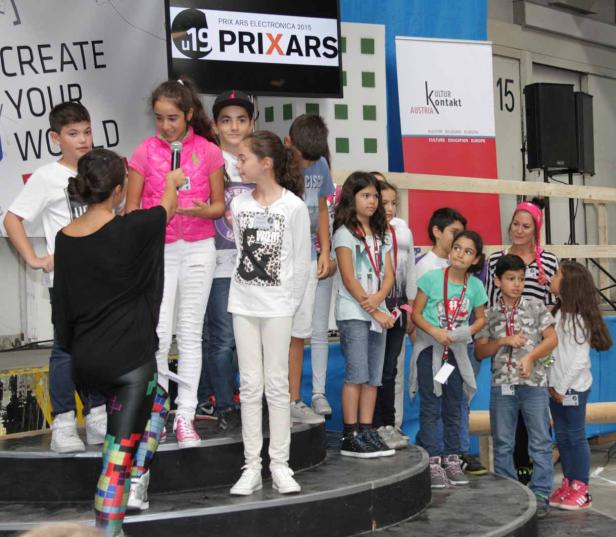 Eine Gruppe Kinder steht auf einer Bühne während des Prix Ars Electronica 2015.