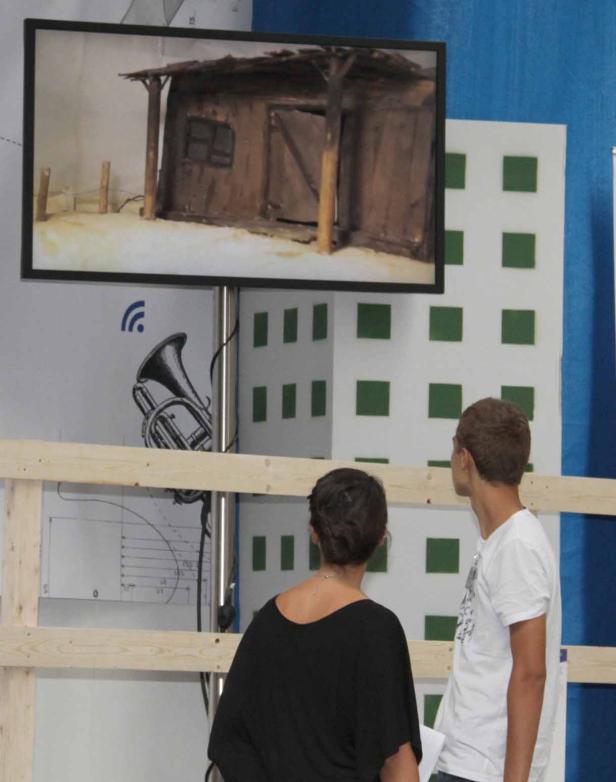 Zwei Personen betrachten ein auf einem Bildschirm angezeigtes Modell eines Holzschuppens.